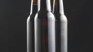 Two beer bottles rotating on black background. video