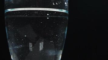 Vaso de agua girando sobre fondo negro