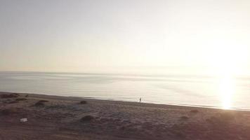 Man running on the beach. Orbital shot with drone video