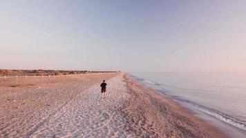 Joven atleta corredor hombre con entrenamiento corporal fuerte en forma en la hermosa puesta de sol en la playa