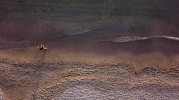 Young man running at shore alone. Top view, Aerial view video