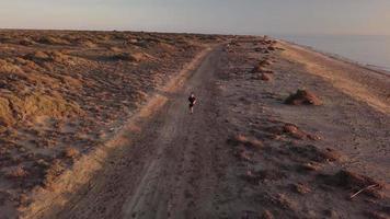 Young man running in the desert landscape video