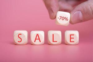 Wooden cubes on a pink background, on them the word SALE is written photo