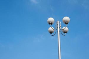 A street lamp composed of four round bulbs under the blue sky