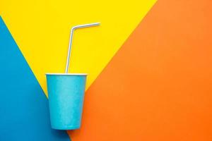 Blue paper cups with drinking colored plastic straws on beautiful multicolored background photo