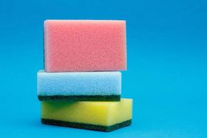 Multicolored sponges for cleaning and washing dishes on a blue background photo