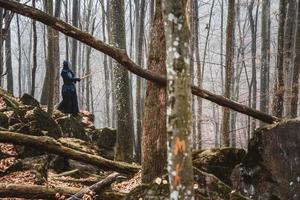 Hombre practicando kendo con espada de bambú shinai sobre rocas y fondo de bosque foto