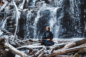 Hombre practicando kendo con espada de bambú sobre fondo de cascada foto