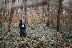 Hombre practicando kendo con espada de bambú shinai sobre fondo de bosque foto