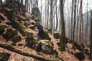 Hombre practicando kendo con espada de bambú shinai sobre rocas y fondo de bosque foto