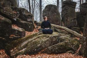 Man in black kimono with a sword meditates and concentrates on rocks and forest background photo