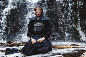 Man practicing kendo with bamboo sword on waterfall background photo