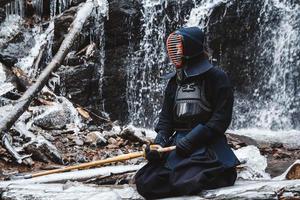 Man practicing kendo with bamboo sword on waterfall background photo