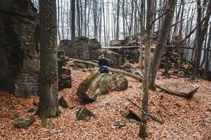 Man in black kimono with a sword meditates and concentrates on rocks and forest background photo