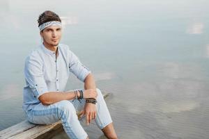Man sitting on wooden bridge and looks at water reflex of blue sky photo