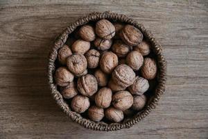 Walnuts in a round wicker basket on a wooden background photo