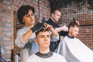 Hairdressers cut their clients in barbershop. Advertising and barber shop concept photo