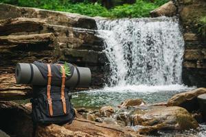 Backpack tourism on background of river and waterfall photo