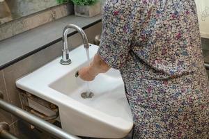 Asian senior or elderly old lady woman patient washing hand by soap and clean water for protect safety infection and kill Novel Coronavirus Covid-19 virus, bacteria and germs. photo