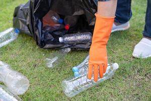 Voluntario de mujer asiática lleva botellas de plástico de agua a la basura de la bolsa de basura en el parque, recicla el concepto de ecología ambiental de residuos. foto