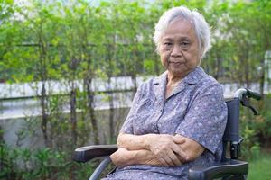 Paciente asiático mayor o mayor de la mujer de la señora mayor en silla de ruedas en el parque, concepto médico fuerte sano. foto