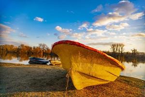 Viejo barco amarillo en el suelo junto al lago foto