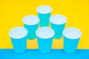 Blue paper disposable cups yellow and blue background photo