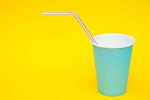 Blue paper cups with drinking colored plastic straws on yellow background photo