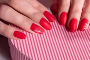 Red matte manicure on female hands for valentines day photo