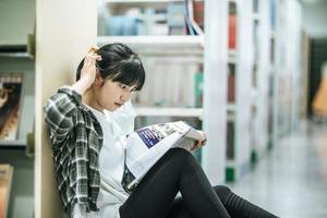 A woman sitting reading a book in the library.