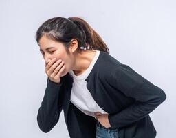 A woman with a stomachache puts her hands on her stomach and covers her mouth. photo