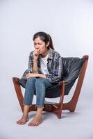 A woman sitting in a chair with abdominal pain and pressing her hand on her stomach photo