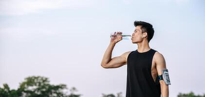 Men stand to drink water after exercise photo