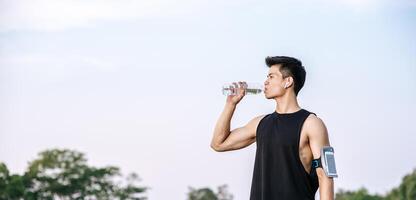Men stand to drink water after exercise photo
