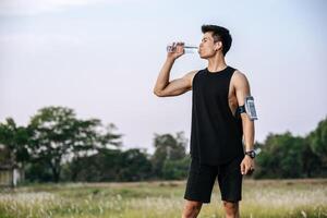 Men stand to drink water after exercise photo