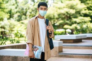 Men wear masks, carry books, and carry a backpack on the stairs. photo