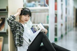 una mujer sentada leyendo un libro en la biblioteca. foto