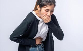 A woman with a stomachache puts her hands on her stomach and covers her mouth. photo