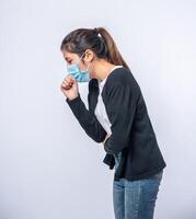 A woman coughing and covering her mouth with her hand photo
