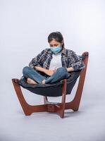 A woman sitting in a chair with abdominal pain and pressing her hand on her stomach photo