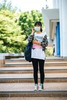 Female students wear masks, stand on stairs and hold books. photo