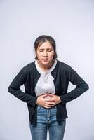 A woman standing with a stomach ache and presses her hand on her stomach. photo