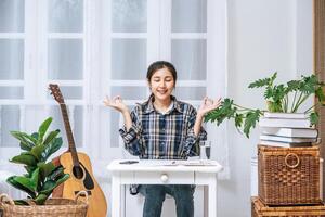 A woman sitting at the table working at the table and making a sign with a hand OK photo