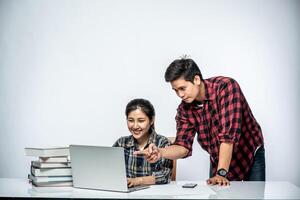 Men teach women how to work with laptops at work. photo