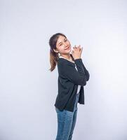 una mujer sonriente felizmente con una camisa negra, jeans de pie, sonriendo felizmente. foto