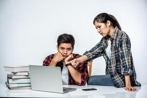 Women teach men how to work with laptops at work. photo