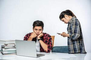 las mujeres enseñan a los hombres cómo trabajar con computadoras portátiles en el trabajo. foto