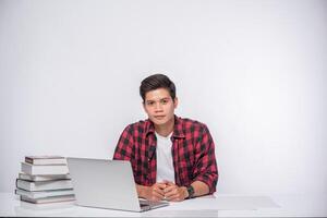 A man wearing a striped shirt uses a laptop to work. photo