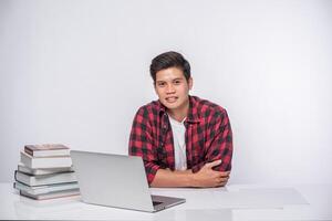 A man wearing a striped shirt uses a laptop to work. photo