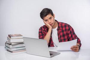 A man using a laptop in the office and doing a document analysis. photo